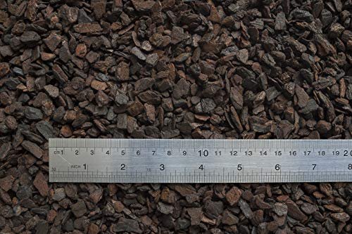 Orchiata orchid bark - Close-up of dark brown pine bark chunks spread flat with a ruler showing particle size scale in centim